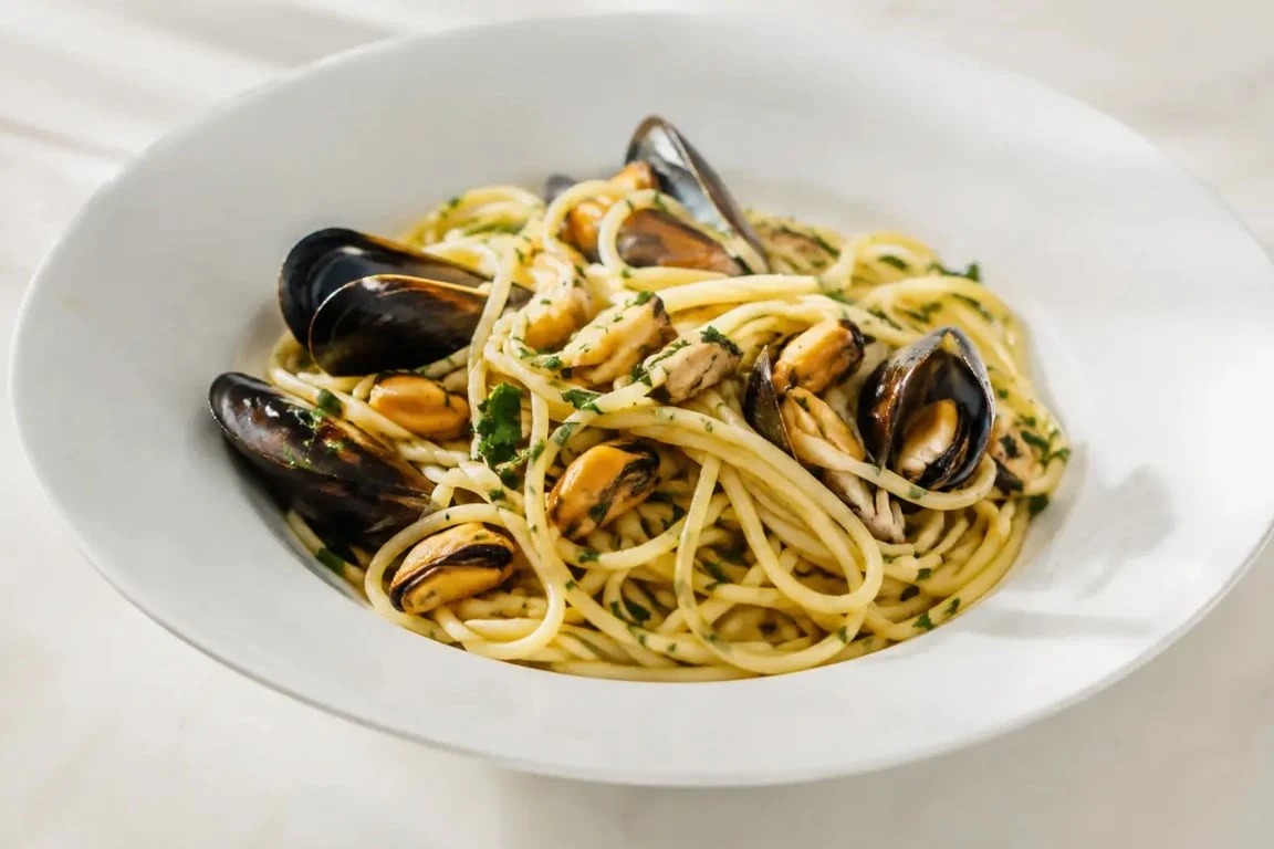 Pates moules à l’ail, au vin blanc et au persil servies dans une assiette